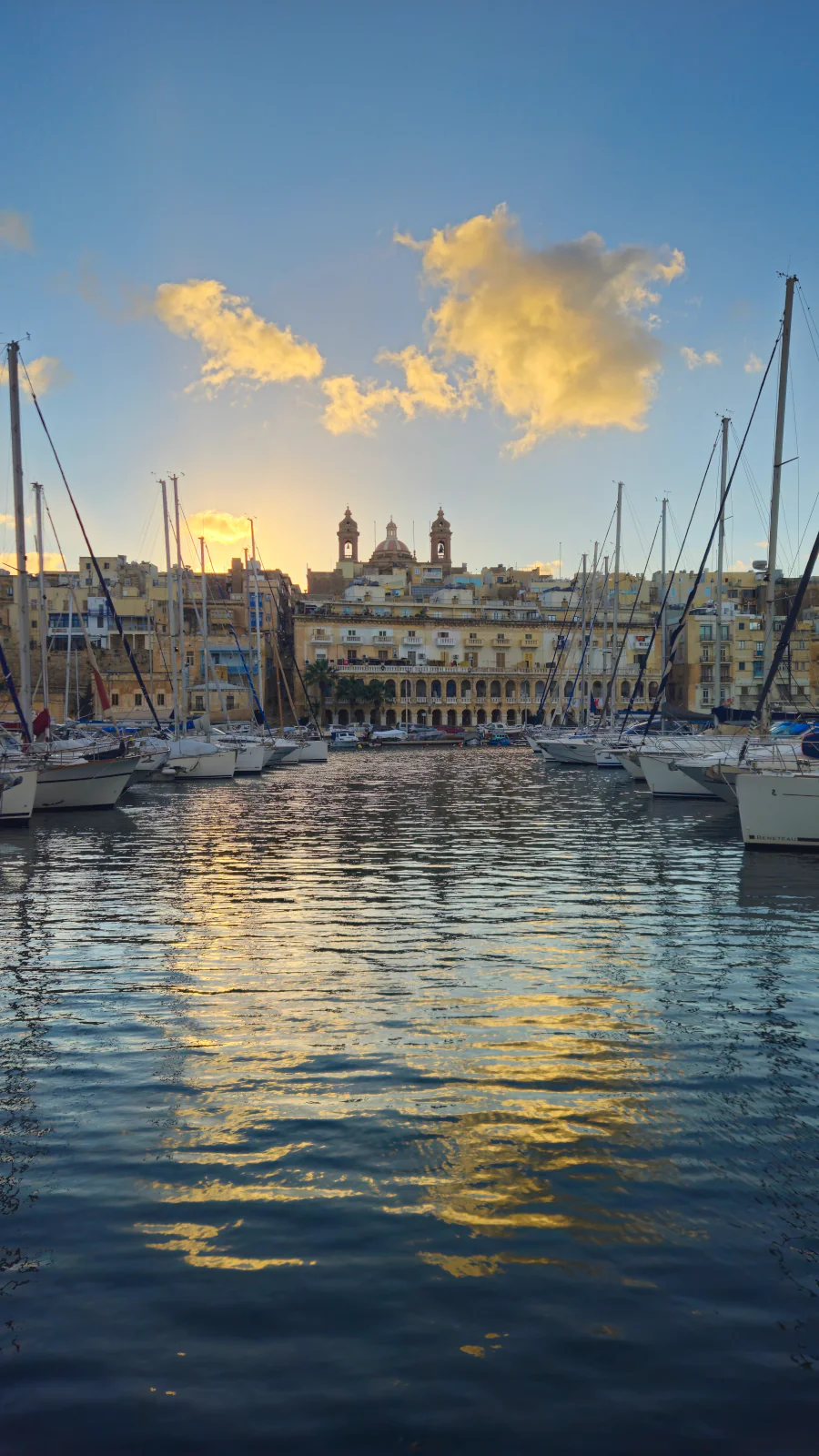 Złoty zachód słońca nad Senglea (Isla) widziany z nabrzeża w Birgu (Trzy Miasta) na Malcie.