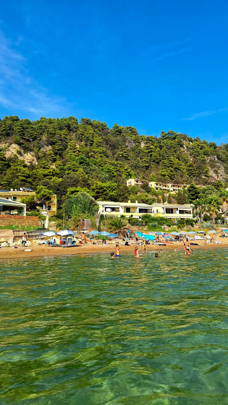Złoty piasek i zielone wzgórza otaczające plażę Glyfada, jedno z najpiękniejszych miejsc na Korfu.