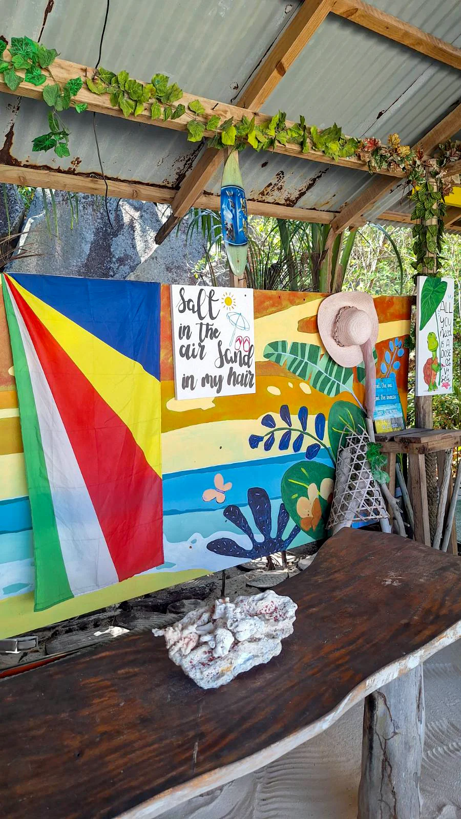Kolorowa flaga Seszeli i dekoracje plażowe z cytatem w tropikalnej chatce przy plaży.