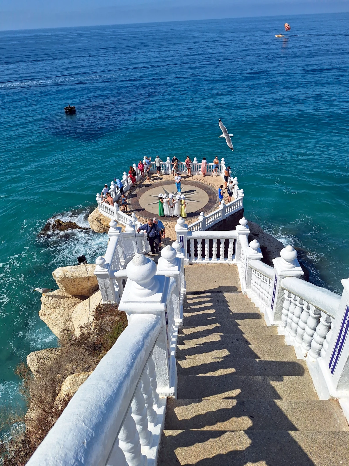 Tourists admiring the ocean from the beautiful white Balcon del Mediterraneo viewpoint in Benidorm.