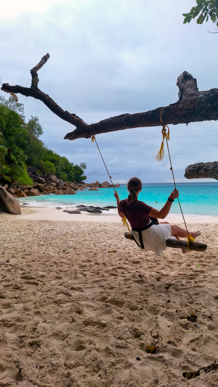 Joanna z Millennials Do Travel relaksująca się na rustykalnej huśtawce na pięknej plaży z białym piaskiem na Praslin na Seszelach.