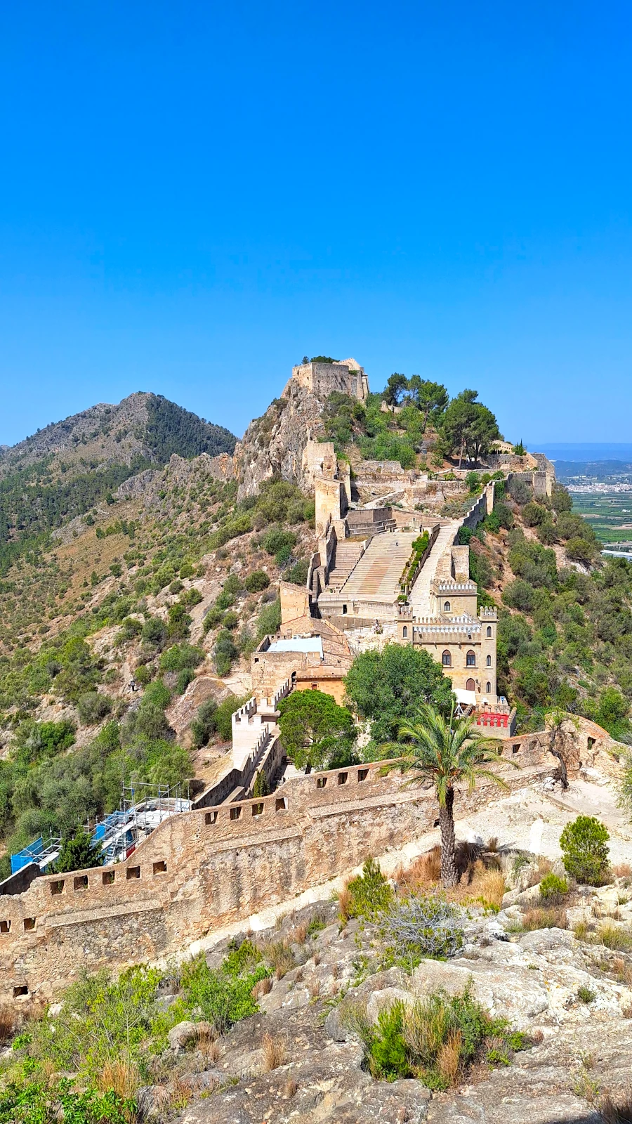 Massive stone walls of the Castell de Xativa stretching along the rugged mountain ridge in Spain.