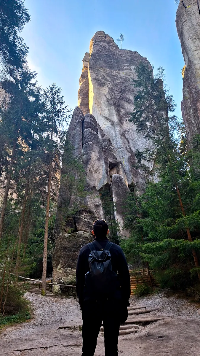 Adam from Millennials Do Travel standing in front of a massive sandstone pillar in Adršpach Rock City.