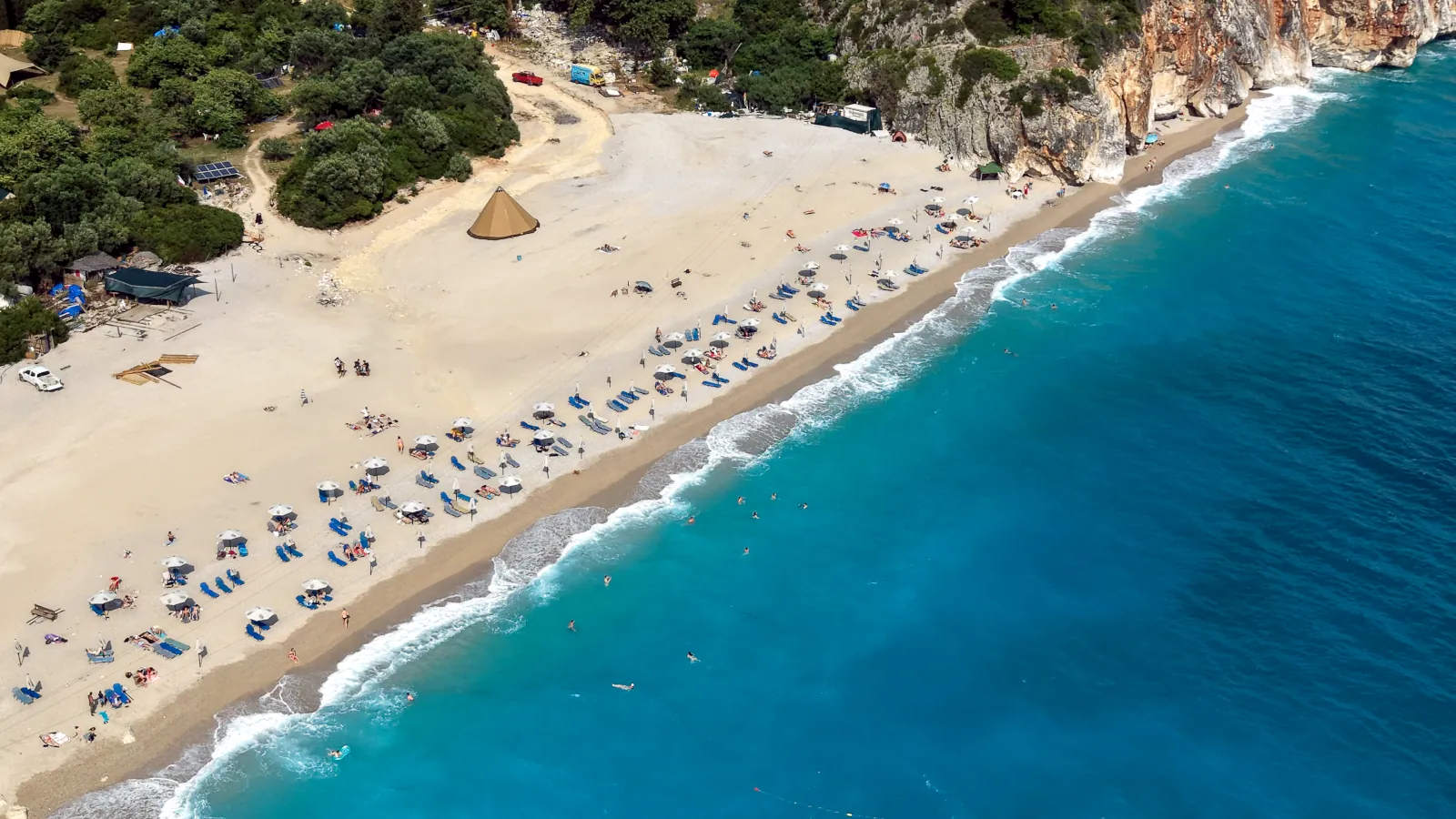 Aerial drone view of Gjipe Beach in the Albanian Riviera, a beautiful pebble beach surrounded by a deep canyon.