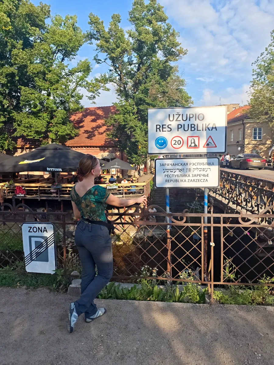 Asia from Millennials Do Travel standing by the Užupio Res Publika sign at the bridge entering the Užupis district in Vilnius.