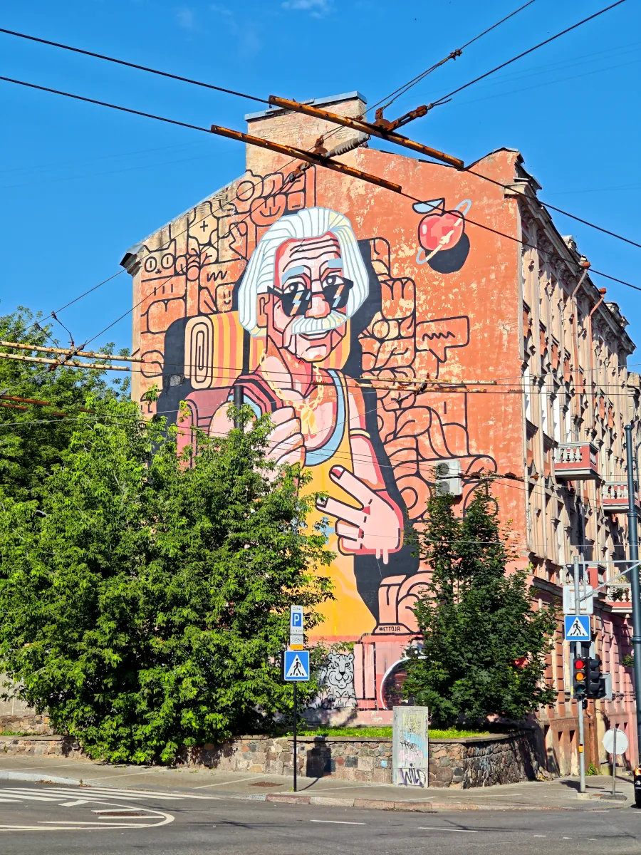 Colorful street art mural depicting Albert Einstein with a backpack on a building facade near V. Šopeno street in Vilnius.