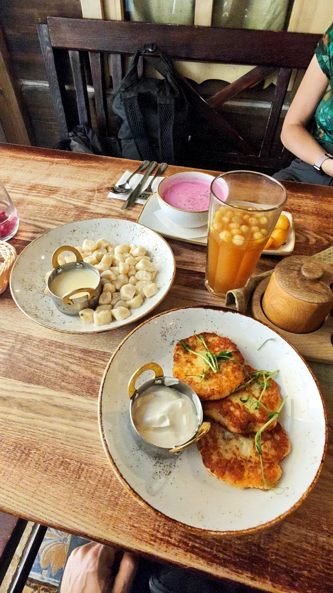 Table with cold beet soup (šaltibarščiai), potato pancakes, and sweet cottage cheese dumplings (varškės virtinukai) at Etno Dvaras.